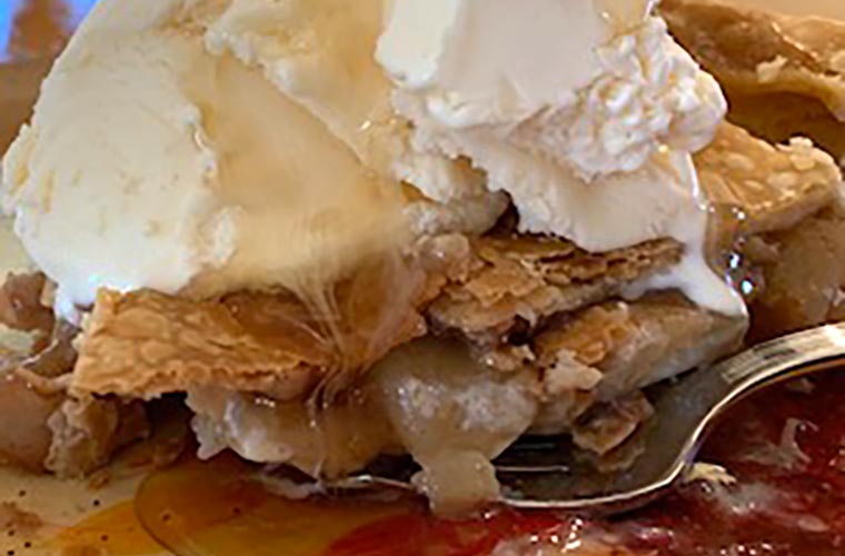 Photo of homemade apple pie with vanilla ice cream and maple syrup