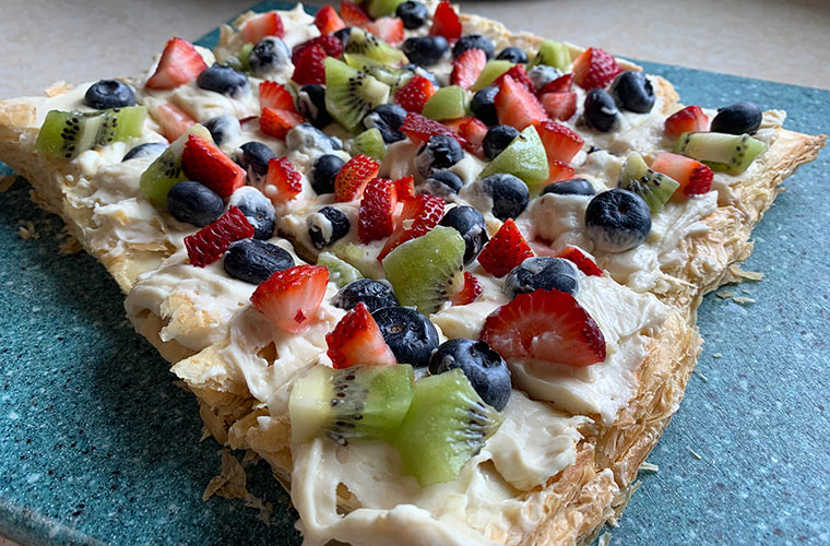 Photo of maple fruit pizza topped with kiwi, blueberries, and strawberries