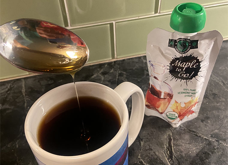 Photo of Maple to-go pouch and coffee with spoon dripping syrup into mug