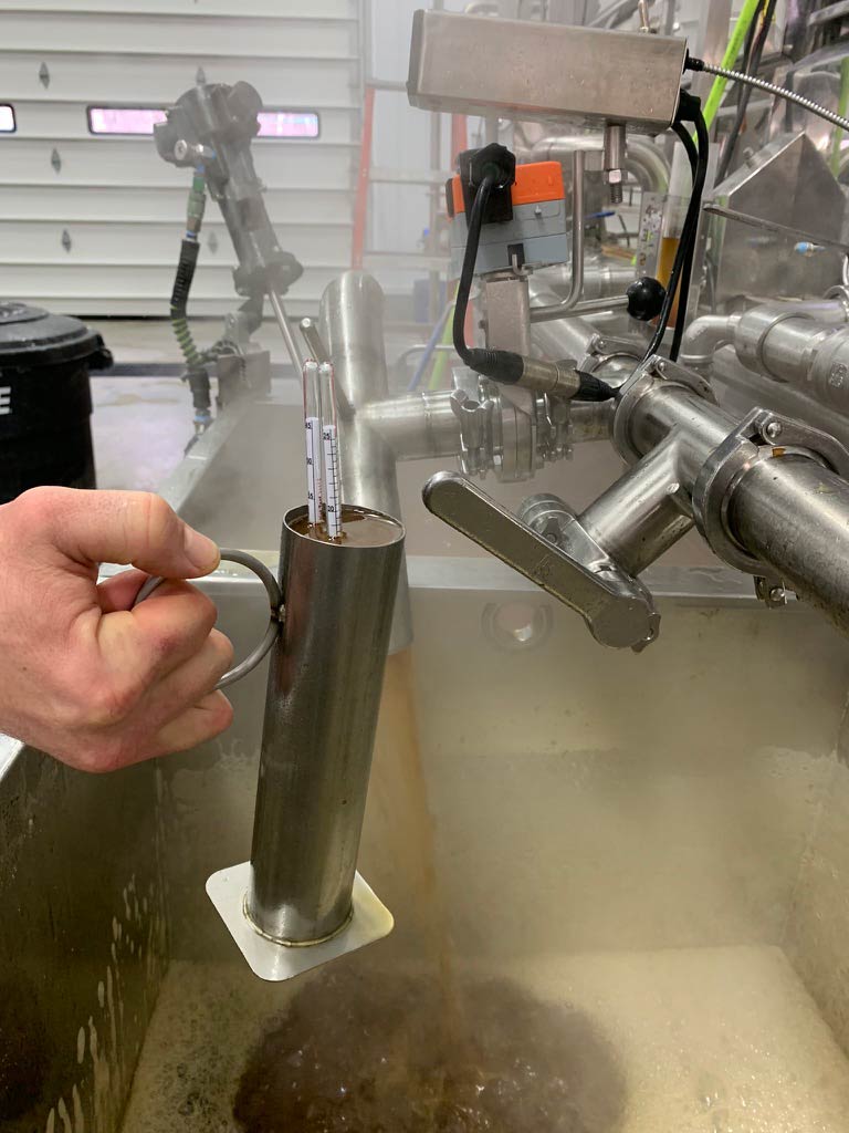A photo of steaming maple syrup being tested in a hand-held metal tube