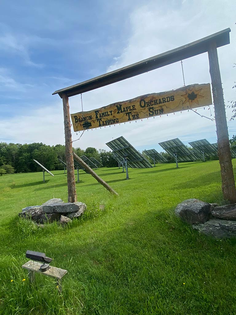 A summer photo of a Branon Family Maple Orchards sign at the solar field on the farm