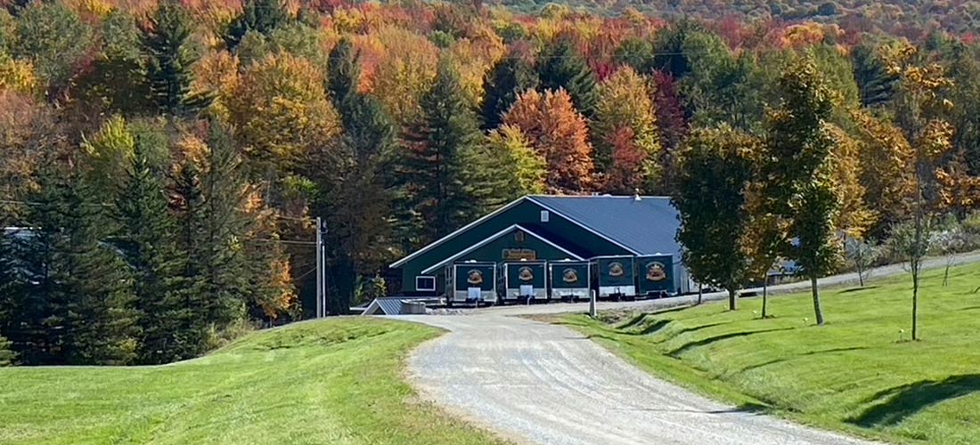 A beautiful autumnal photo of the Branon Family sugarhouse sounded by colorful maple trees